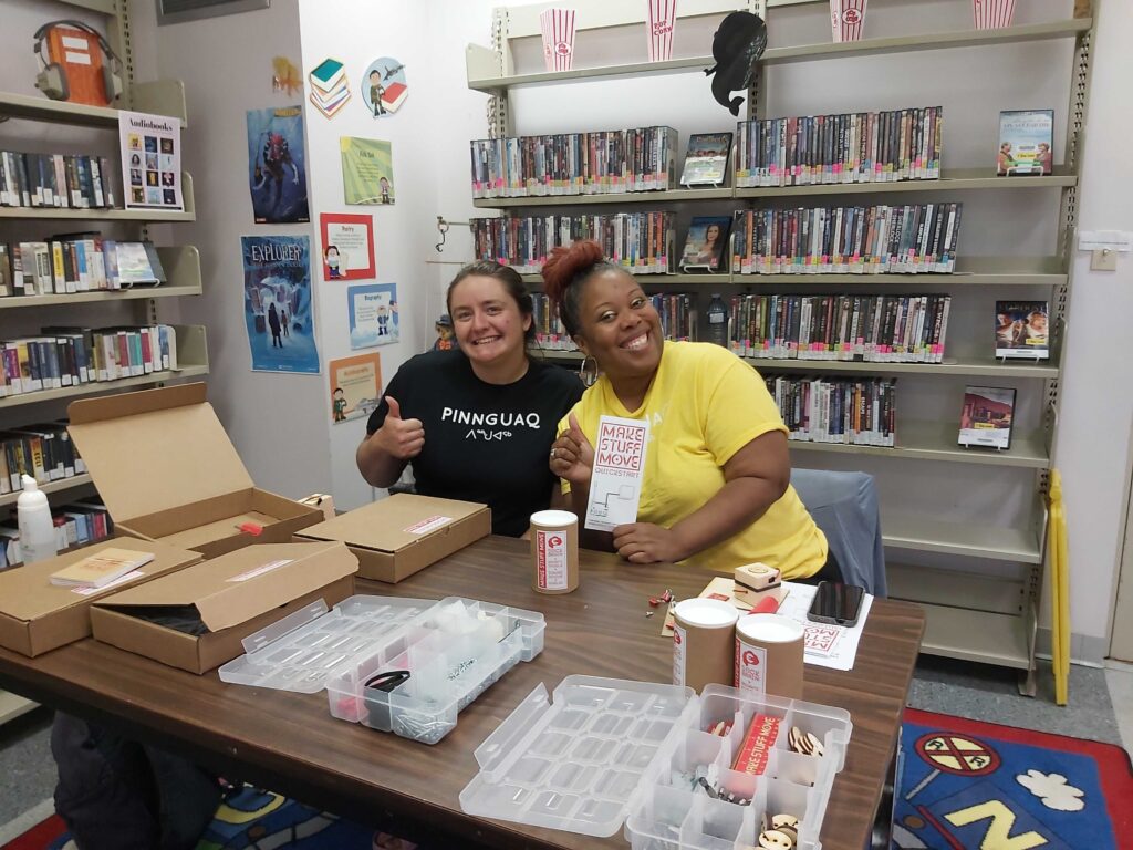 Two Ampere staff members sitting at a table, in a local library.