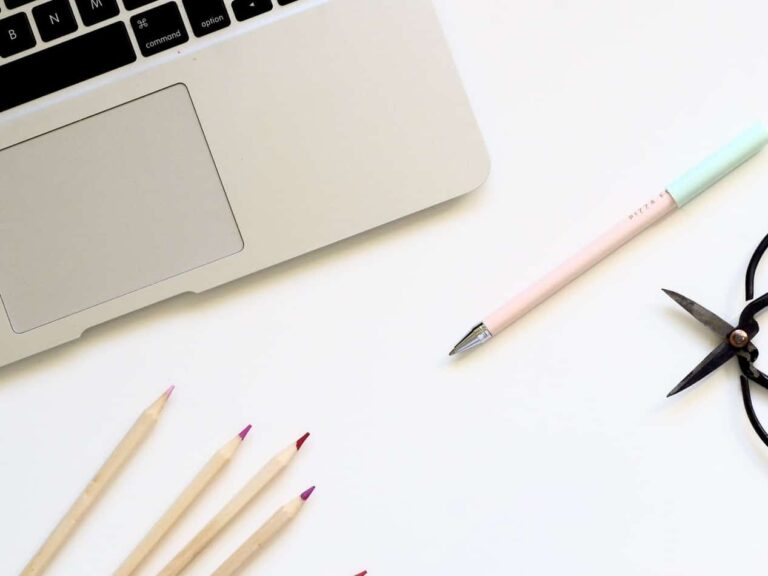 laptop open with pencils and a pen laying in front of it