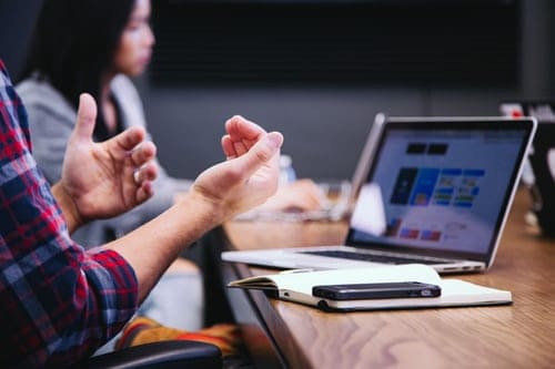 two people talking in front of laptops